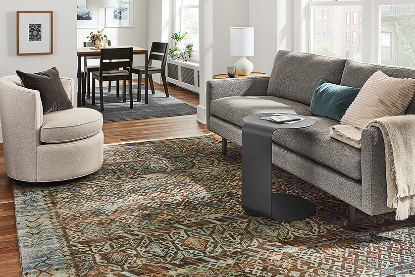 Jasper sofa in Sumner graphite in living room with graphite C-table and Otis swivel chair. Parsons dining table and Afton dining chairs in adjacent dining room.