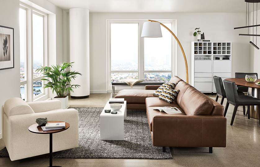 Large apartment living room with Pierson sofa in Laino cognac leather and Harmon chair in Tepic ivory fabric. Decker dining table in background.