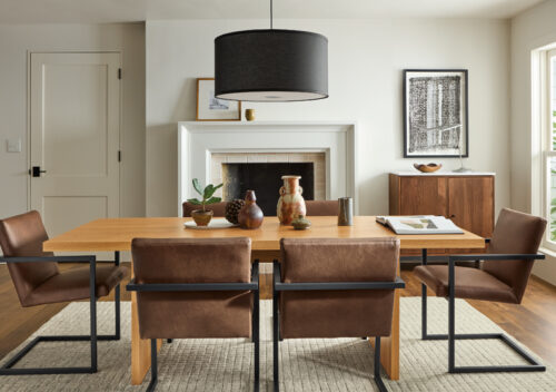 Corbett wood dining table and leather chairs in a dining room with a fireplace.